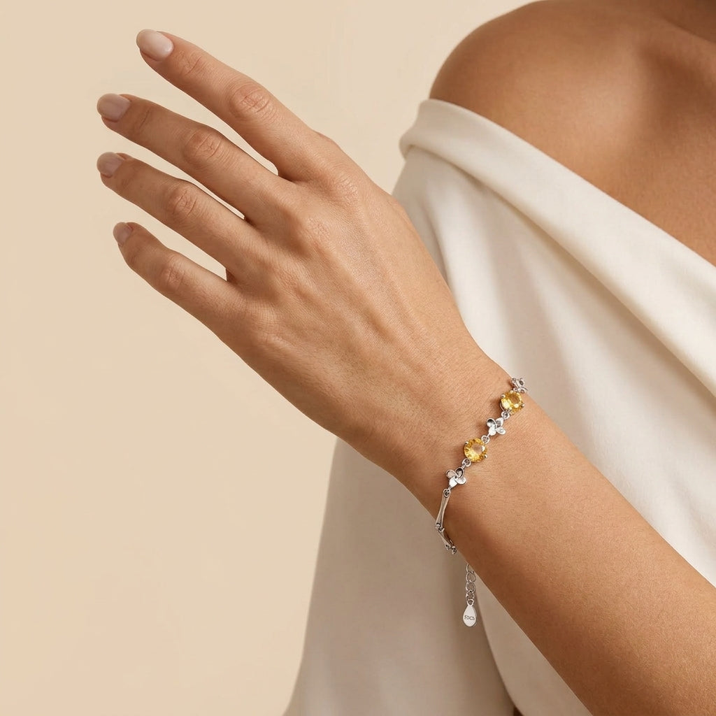 Bracelet Citrine Soleil d’Or en argent porté au poignet d'une femme, mettant en valeur les pierres jaunes éclatantes et les détails floraux du bijou.