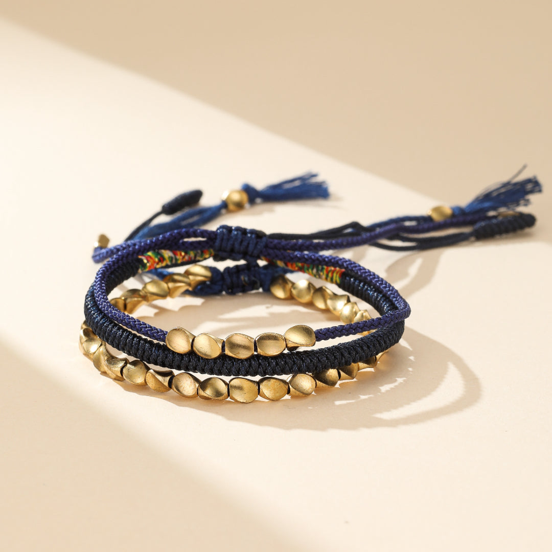 Bracelet Cordon Cuivre Pulse Paix, pierres de cuivre taillées et fil tibétain authentique, ajustable. Bijou énergétique inspiré de l'Himalaya pour équilibre et sérénité.