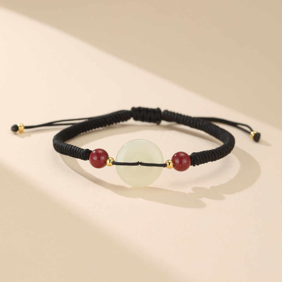 Détail du Bracelet Sérénité en Jade et Cinabre: donut en jade blanc apaisant et perles de cinabre pour l'ancrage, monté sur cordon spirituel.