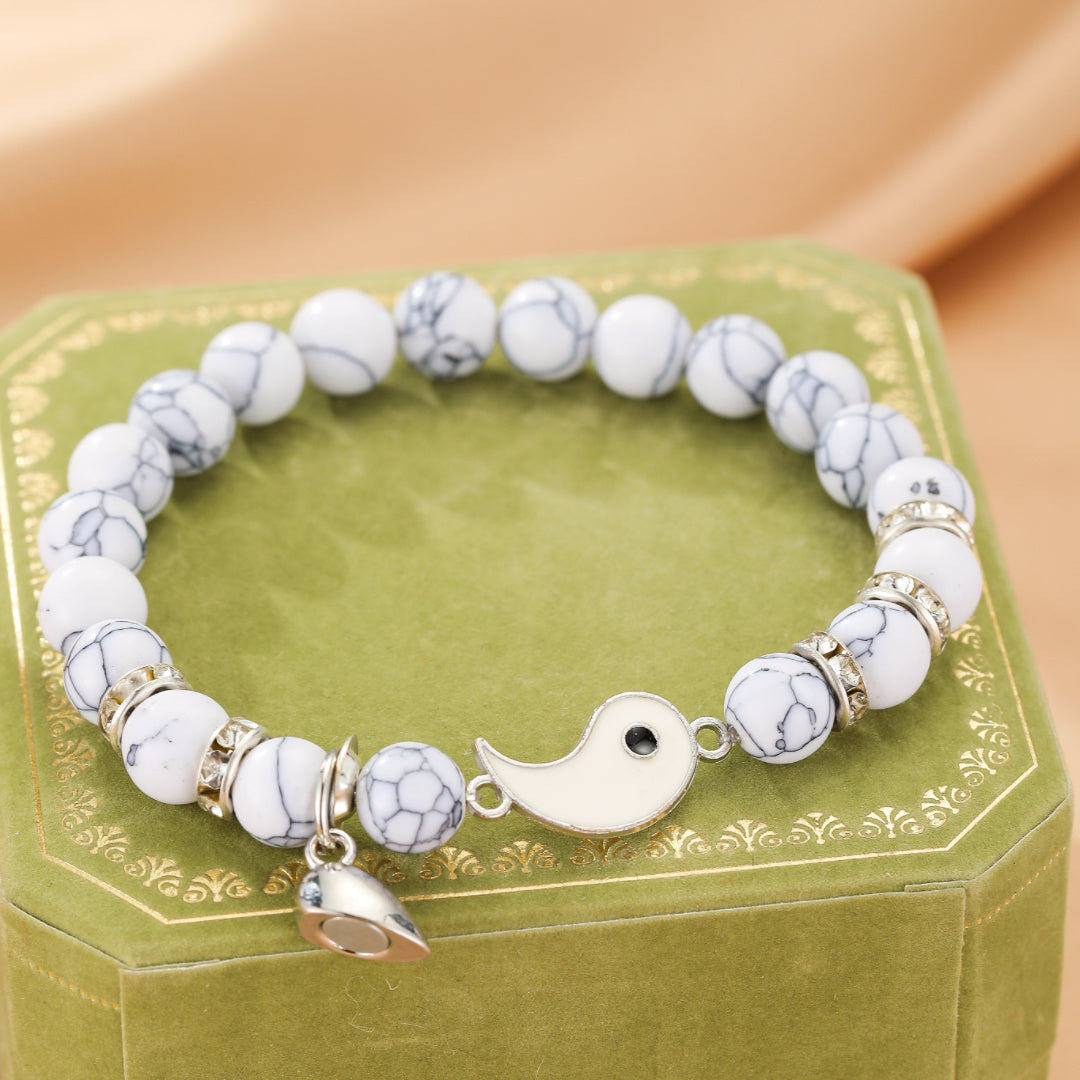Bracelet couple en pierre de lave et howlite avec un pendentif Yin et Yang blanc et un fermoir magnétique.