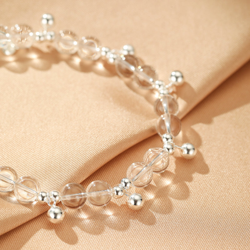 Bracelet fin en argent avec des perles rondes en cristal de roche transparentes et légèrement fumées, alternant avec de petites perles rondes en argent brillant.