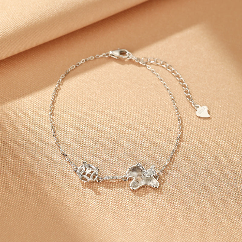 Bracelet en argent avec un pendentif en forme de licorne ailée ornée de cristaux et un pendentif de pièce chinoise porte-bonheur.