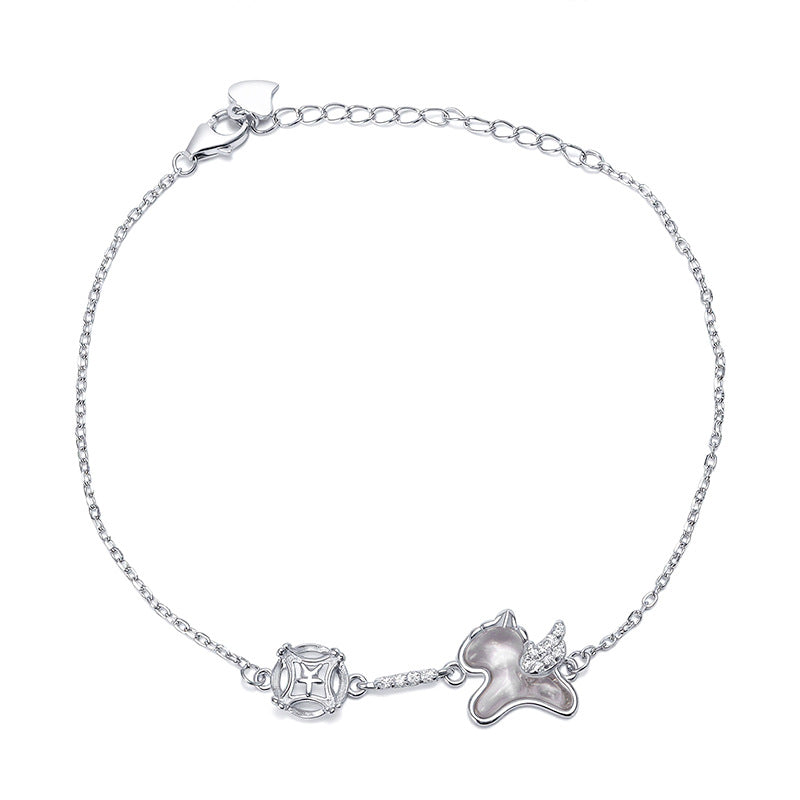Bracelet en argent avec un pendentif en forme de chat ailé et un pendentif rond orné d'un motif géométrique.