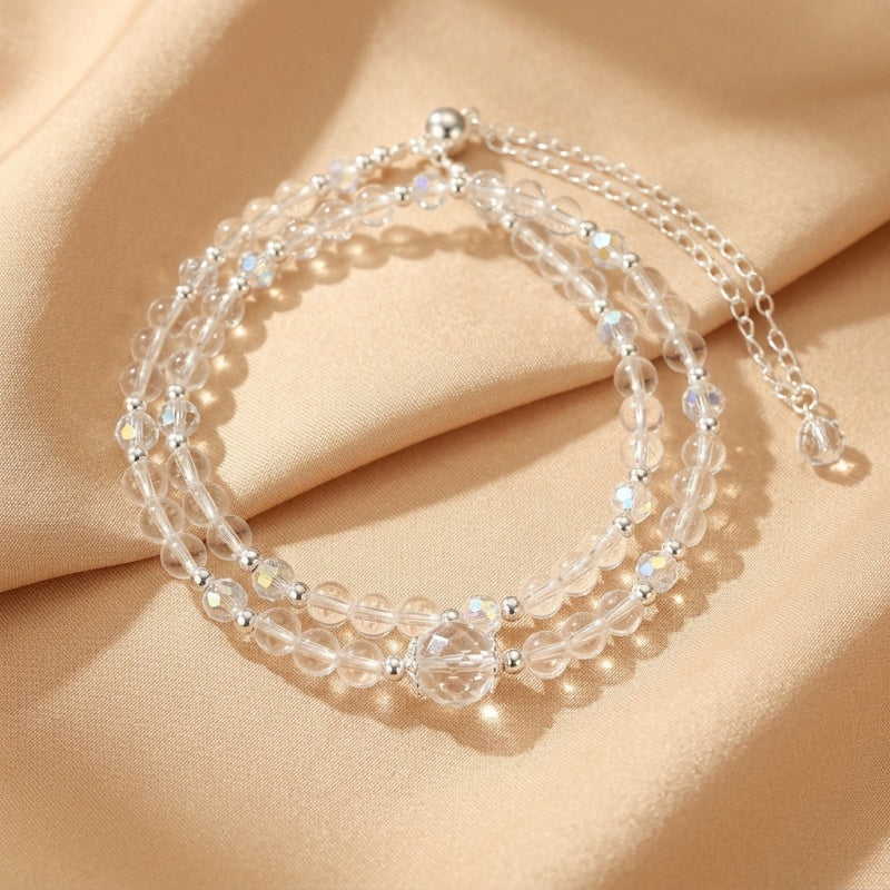 Bracelet double rang en cristal de roche clair et perles argentées, avec un fermoir ajustable et une breloque centrale facettée.