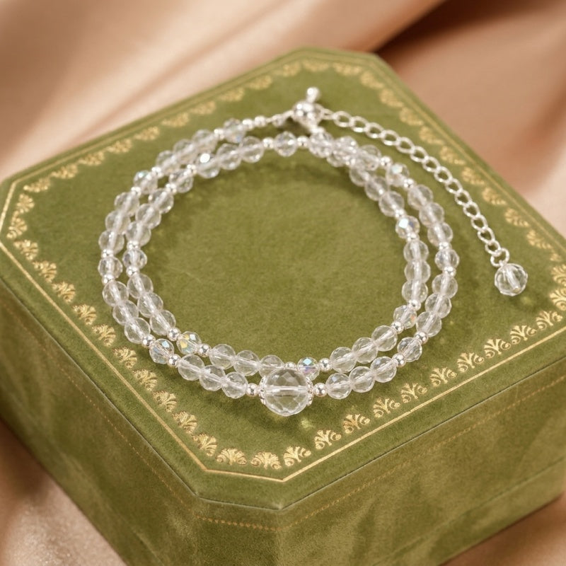 Bracelet double rang en cristal de roche transparent et petites perles argentées, avec un fermoir à chaîne réglable.