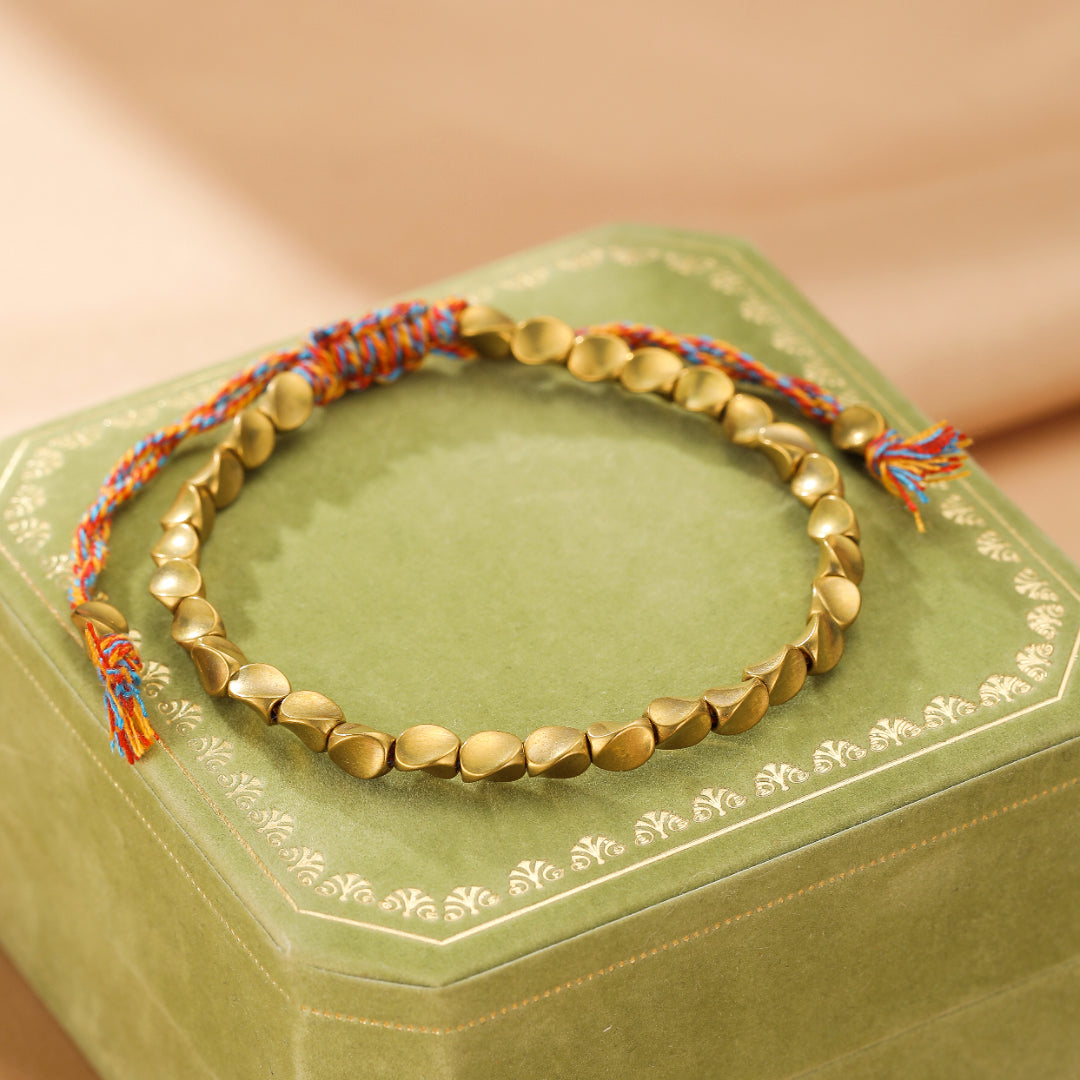 Bracelet en cuivre avec perles mates et cordon tressé multicolore orange, bleu et rouge.