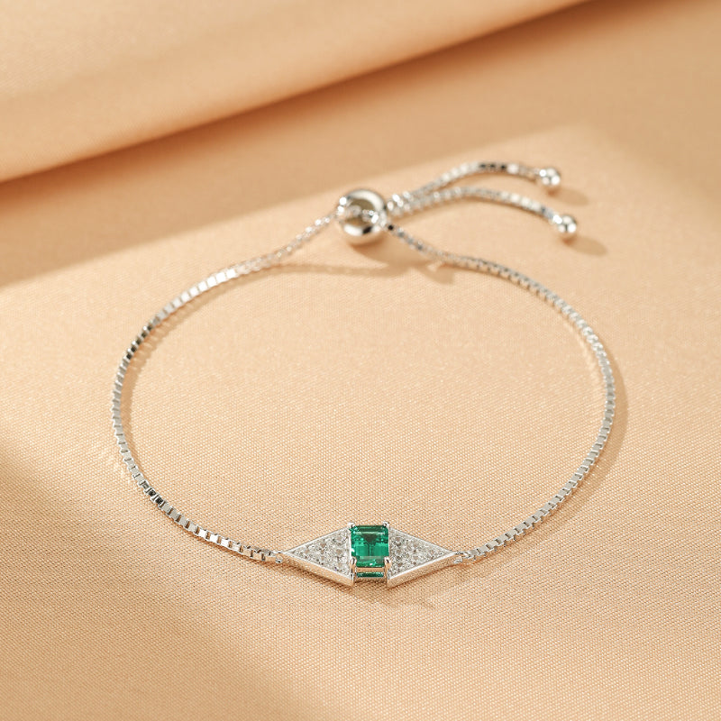 Bracelet ajustable en argent 925 avec une émeraude rectangulaire centrale et des diamants incrustés dans un design géométrique en losange.