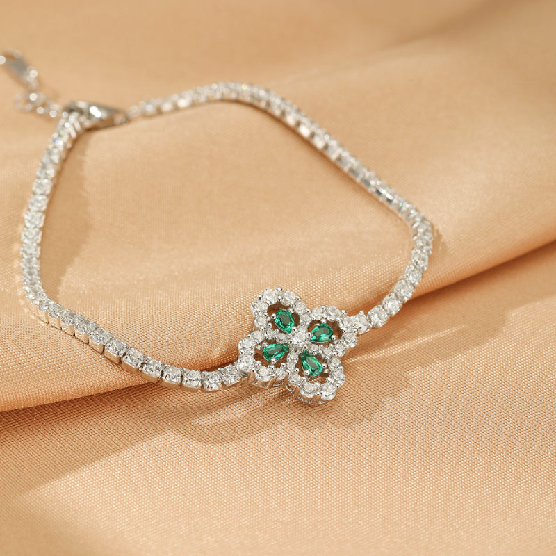 Bracelet Tennis en argent 925 avec un pendentif trèfle serti de pierres d'émeraude et de diamants scintillants.