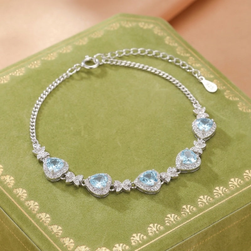 Bracelet en argent Sterling 925 orné de cinq cœurs bleu clair sertis de zirconiums cubiques scintillants, disposés sur une chaîne délicate.