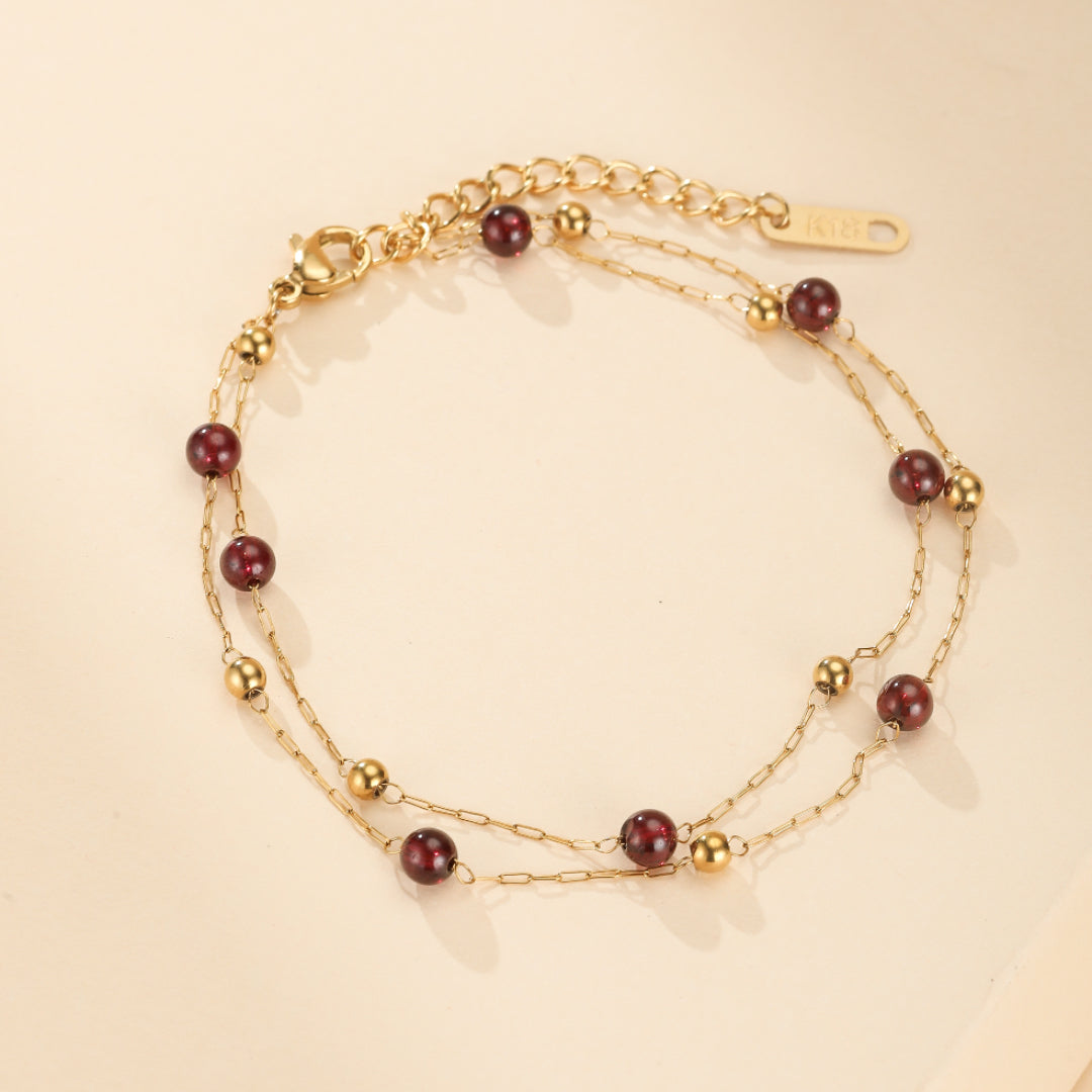 Bracelet double rang en plaqué or 18K avec perles de grenat rouge foncé et petites perles dorées.