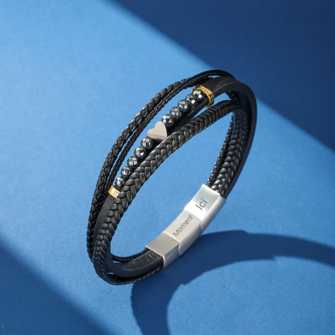 Bracelet multicouche pour homme en cuir noir tressé, orné de perles d'hématite, d'un pendentif en forme de cœur argenté et d'un fermoir gravé « Moment Ici ».