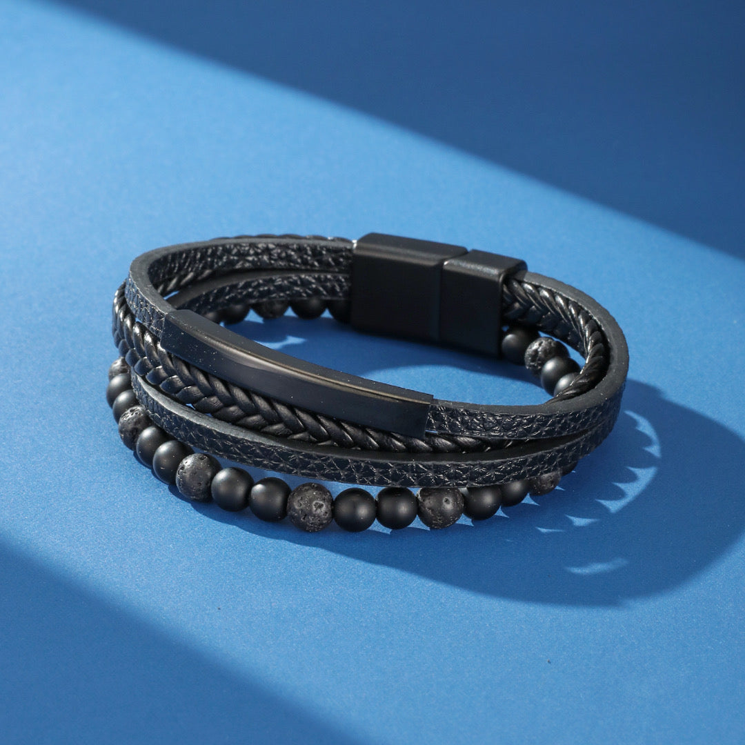 Bracelet homme cuir "Équilibre Sombre" composé de cuir tressé noir, de perles de lave et d'une barre métallique sobre, avec fermoir magnétique.