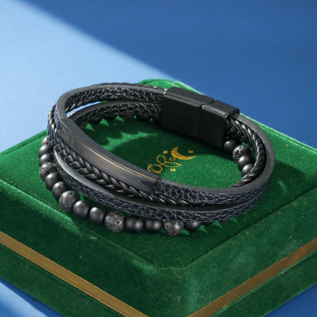 Bracelet homme cuir noir tressé avec perles de lave et fermoir magnétique, sur coffret vert.