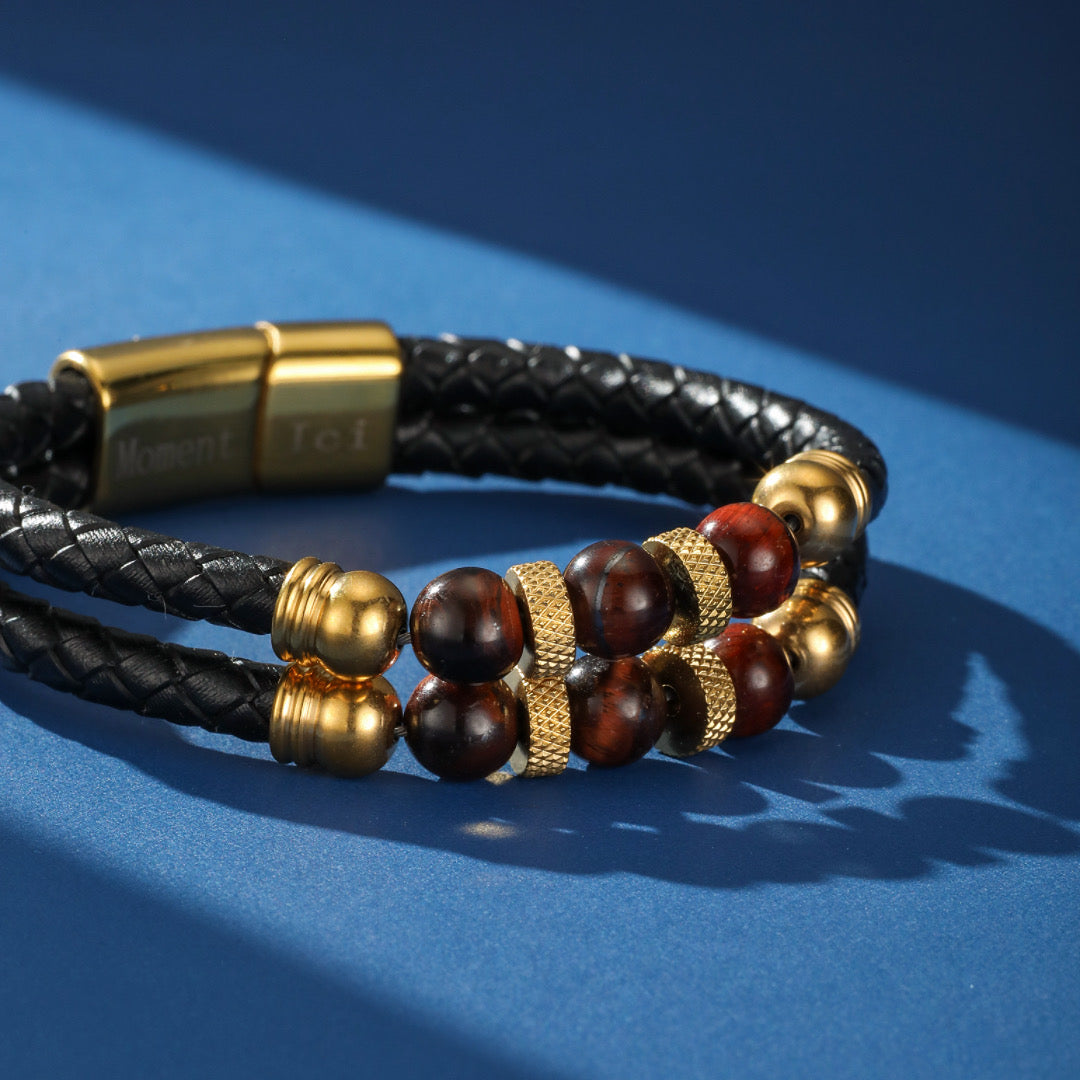 Bracelet double rang en cuir tressé noir pour homme, orné de perles œil de tigre et de détails dorés, avec un fermoir magnétique gravé.