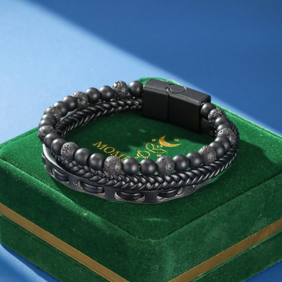 Bracelet homme cuir "Ombre Protectrice" avec perles de lave et fermoir magnétique sur un écrin vert.