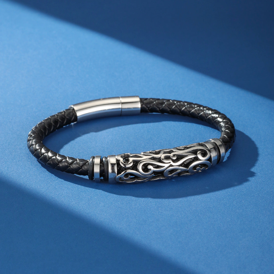 Bracelet homme en cuir tressé noir avec tube central en acier inoxydable orné de motifs tribaux et fermoir magnétique.