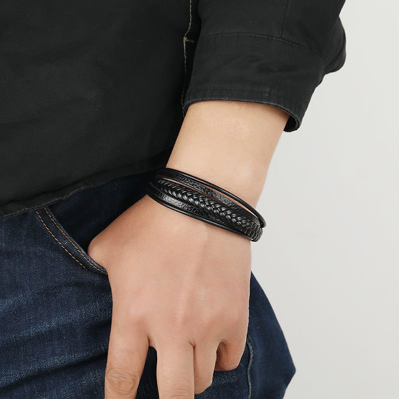 Bracelet homme enveloppant multicouche en cuir noir, texture tressée, porté au poignet.