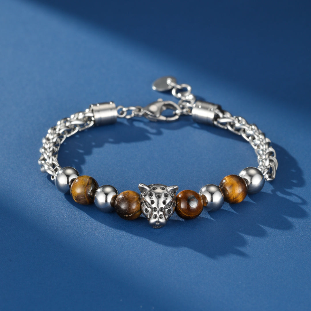 Bracelet pour homme en œil de tigre et argent avec une tête de léopard stylisée, sur fond bleu.
