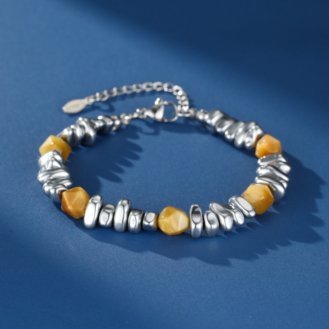 Bracelet homme Prisme Minéral avec perles d'œil de tigre facettées et éléments métalliques argentés texturés, sur fond bleu uni.
