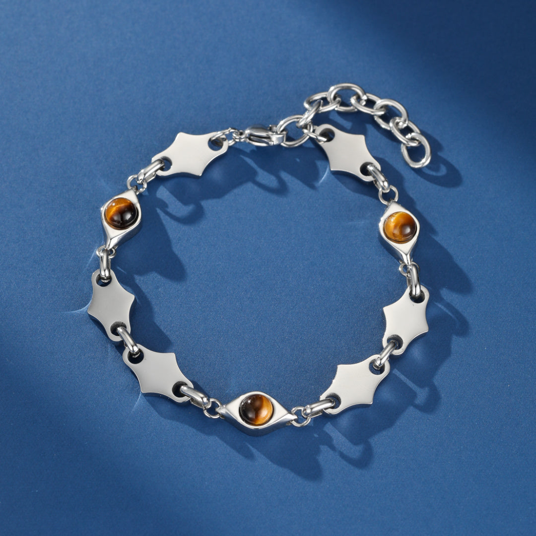 Bracelet homme argenté avec des pierres d'œil de tigre et un design de maillons en forme d'étoile sur fond bleu.