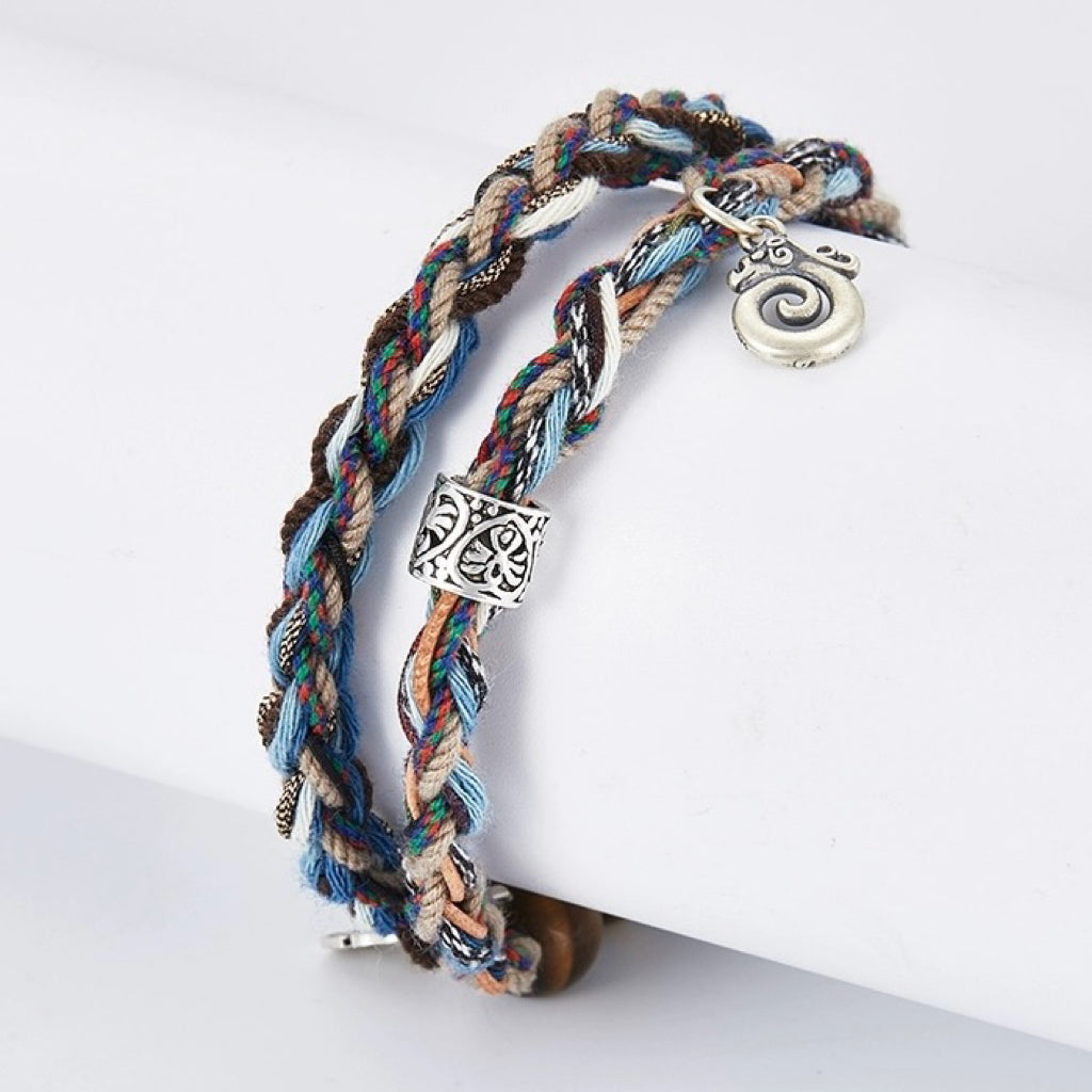 Bracelet tressé multicolore avec breloque spirale argentée et perle ornée, style aventurier.