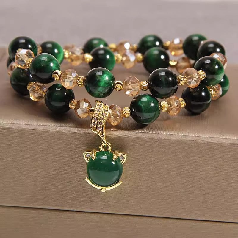 Deux bracelets superposés en œil de tigre vert et perles de cristal dorées, ornés d'un pendentif en forme de tête de chat stylisée en jade vert et or, serti de diamants.