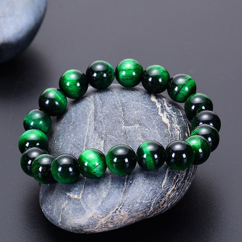 Bracelet en œil de tigre vert sur une pierre grise, symbole de force et de courage.