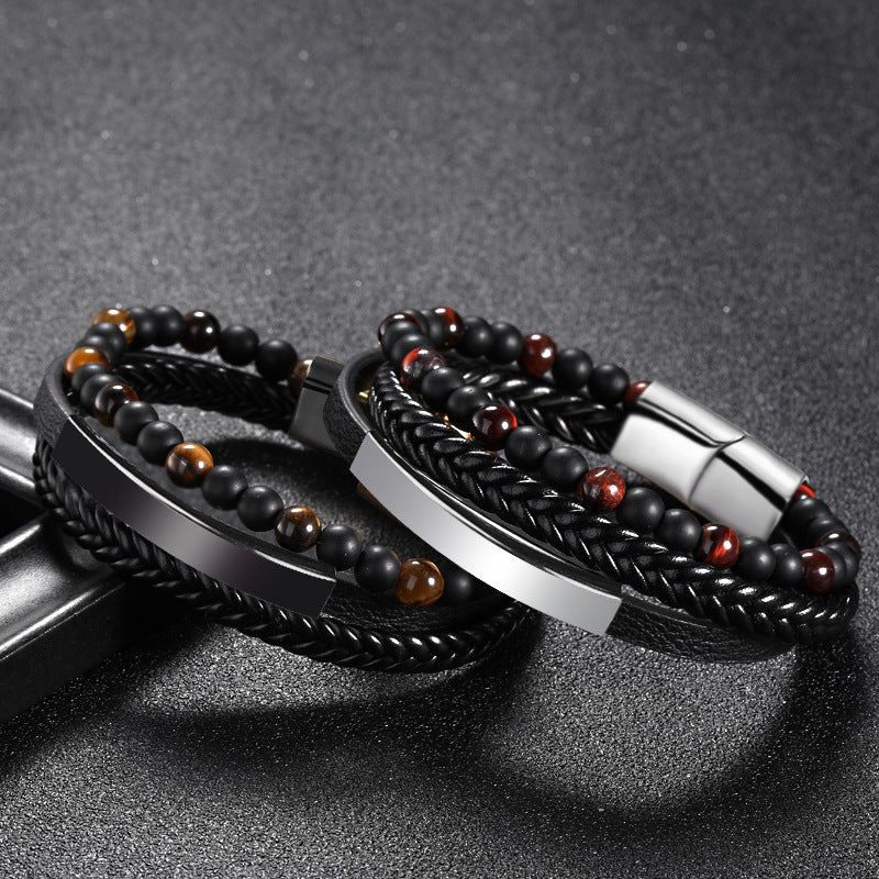 Deux bracelets superposés, l'un en cuir tressé noir orné de perles œil de tigre et d'un fermoir métallique, l'autre en cuir tressé noir avec des perles sombres et rouges, et un fermoir argenté.