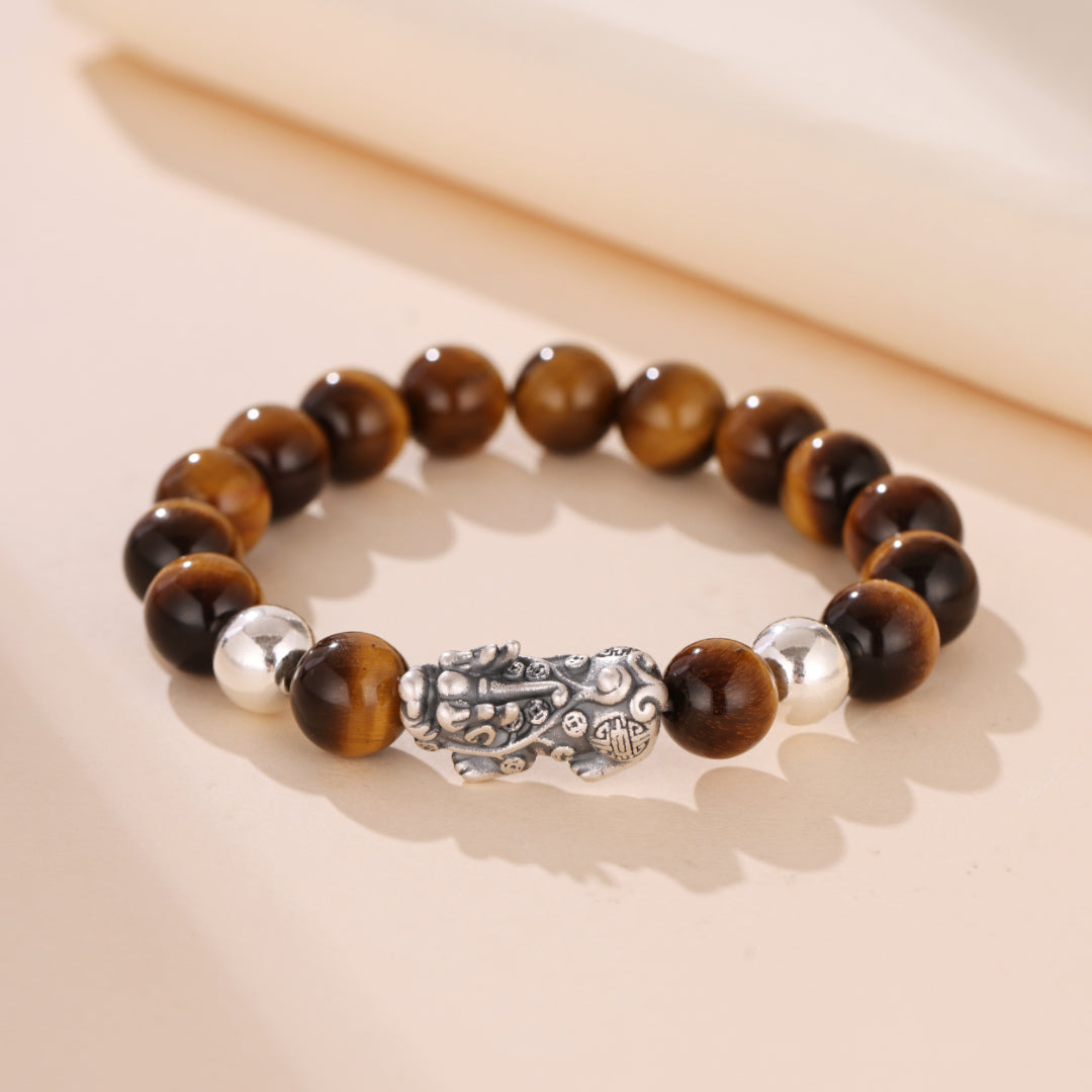 Bracelet en œil de tigre avec perles marron et argentées et un fermoir en forme de créature mythique, style Puissance Mystique.
