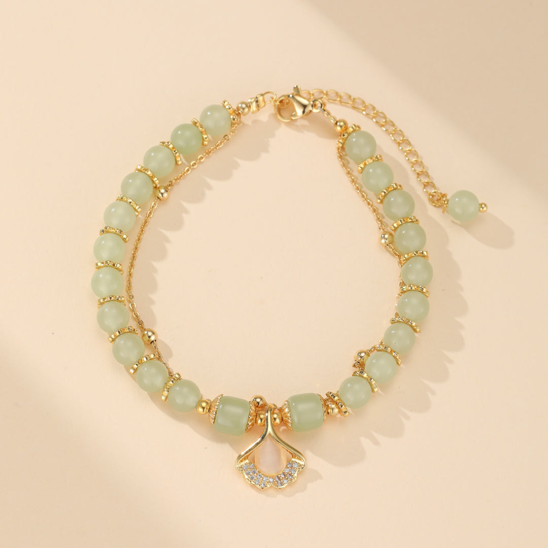 Bracelet en jade vert et feuille de ginkgo en argent plaqué or, ajustable (18+5cm), symbolisant l'amour, la paix et l'harmonie. Idéal pour le bien-être et l'équilibre intérieur.