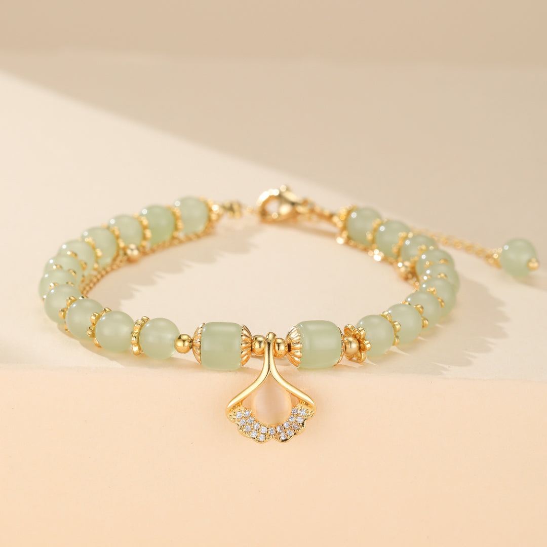 Bijou élégant: bracelet en argent plaqué or avec perles de jade purifiant et pendentif feuille de ginkgo pour la tranquillité. Un accessoire spirituel et raffiné pour femme.