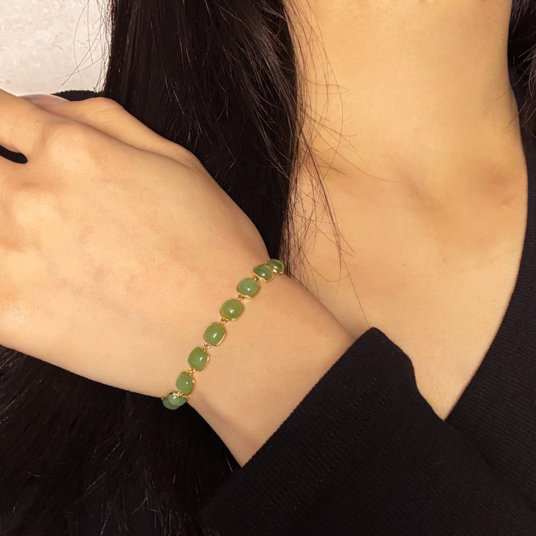Bracelet "Perle de Lumière" en jade et argent plaqué or, porté au poignet d'une femme.