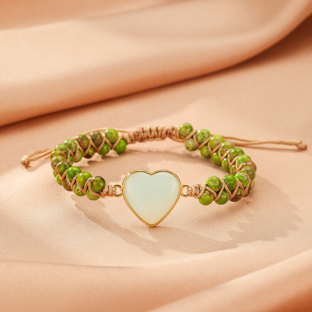 Bracelet en jaspe vert avec un pendentif en forme de cœur blanc et un cordon tressé marron.