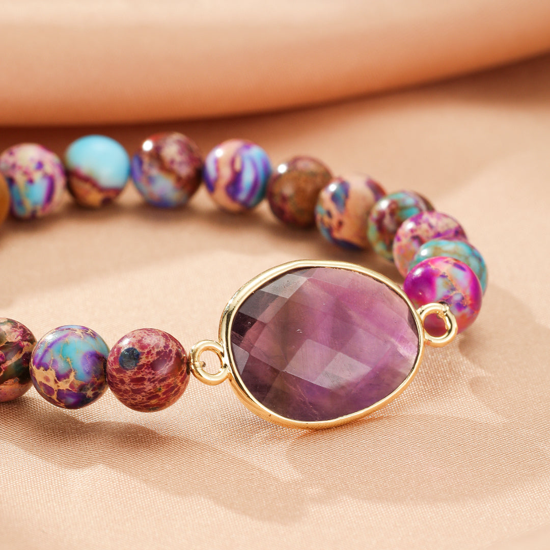 Bracelet en jaspe impérial avec une pierre centrale violette facettée et des perles multicolores aux teintes de bleu, violet et marron.