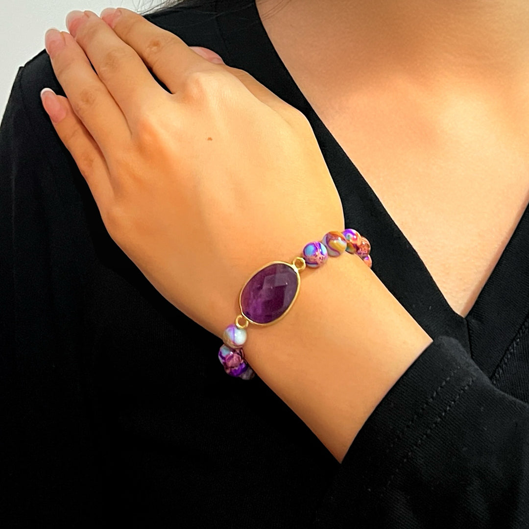 Bracelet "Éveil des Sens" en jaspe violet avec une pierre centrale facettée et des perles multicolores sur un poignet féminin