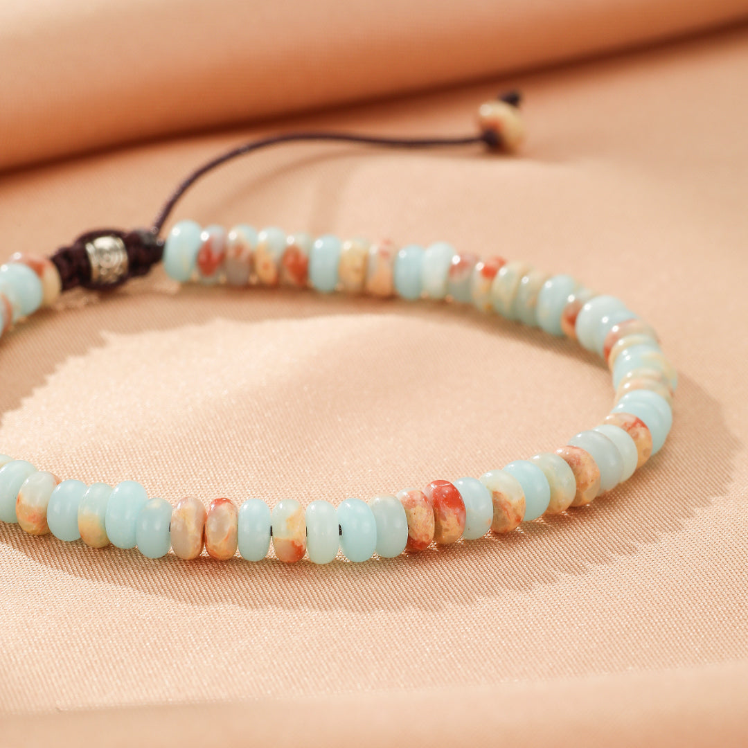 Bracelet en jaspe bleu ciel et orange avec fermoir réglable en fil noir et perles intercalaires métalliques.
