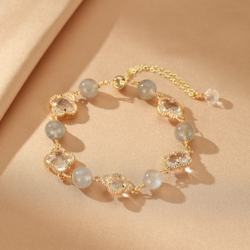 Bracelet en plaqué or avec des perles rondes de labradorite et des cristaux taillés en forme de trèfle à quatre feuilles, un bijou porte-bonheur.