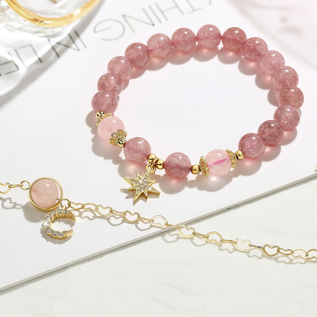 Bracelet de perles en quartz fraise avec breloques étoile et lune, monté sur une chaîne fine plaquée or.