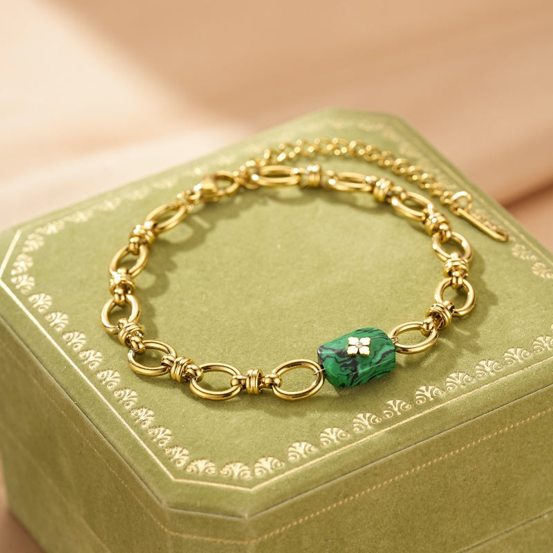 Bracelet en plaqué or avec un pendentif en malachite verte orné d'une petite fleur blanche.