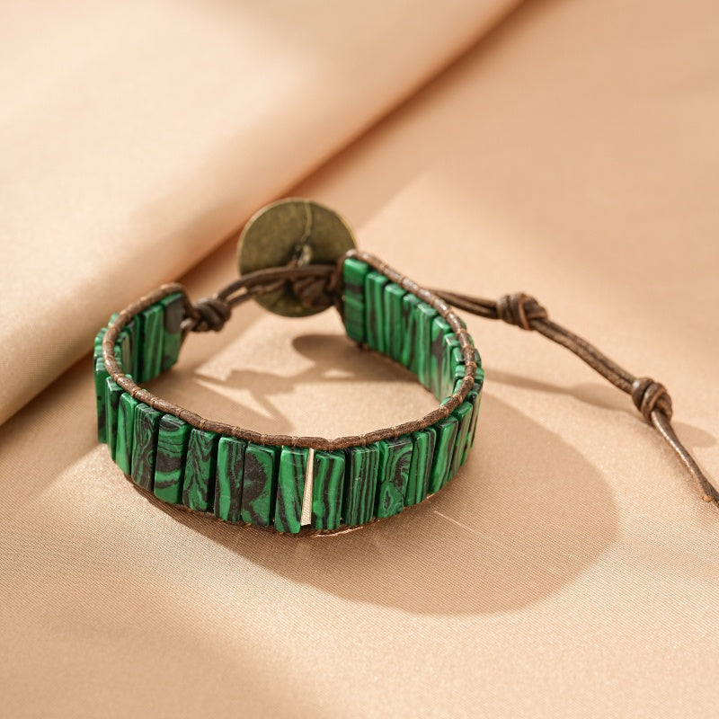 Bracelet en pierre de malachite verte à bandes noires, monté sur un cordon en cuir marron avec un fermoir en métal vieilli.