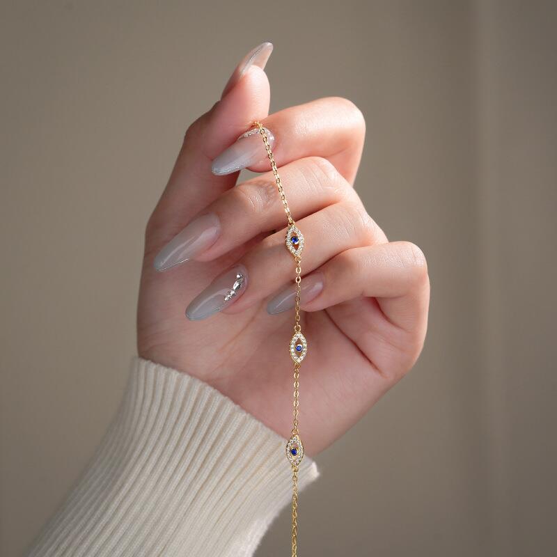 Bracelet œil bleu et diamants en plaqué or sur une main féminine