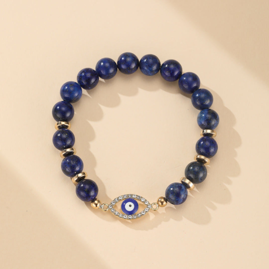 Bracelet œil bleu et doré en lapis-lazuli, orné d'une amulette œil-du-malheur incrustée de strass.