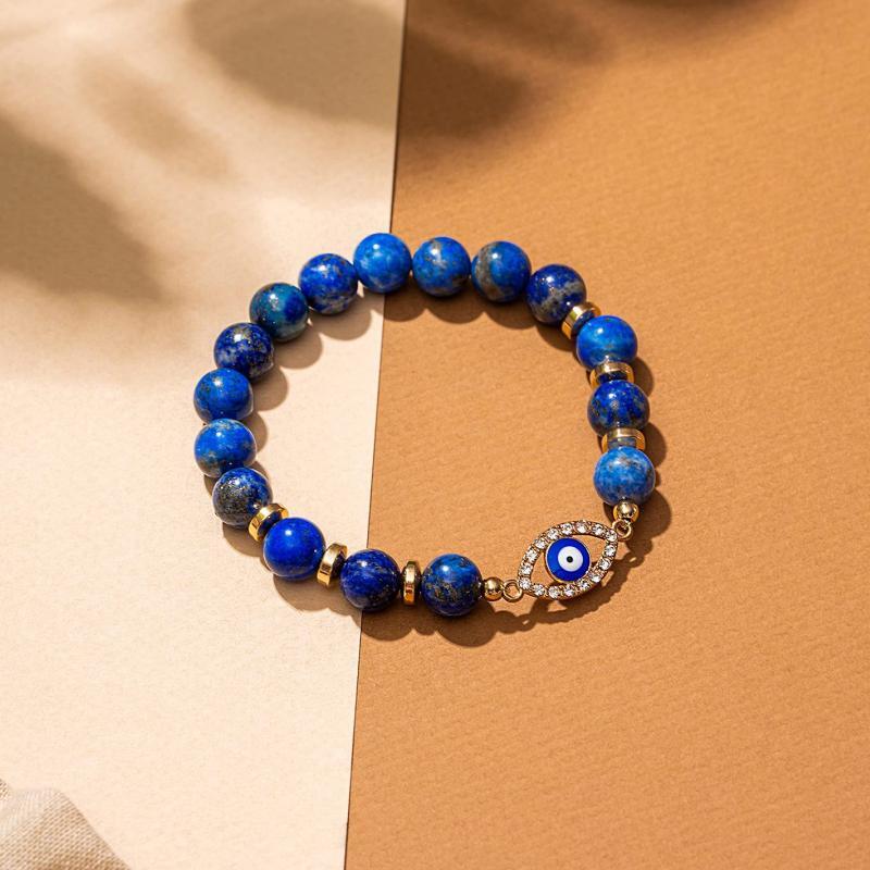 Bracelet œil du mal en lapis-lazuli avec des perles bleues et dorées, orné d'un pendentif œil bleu et blanc incrusté de strass.
