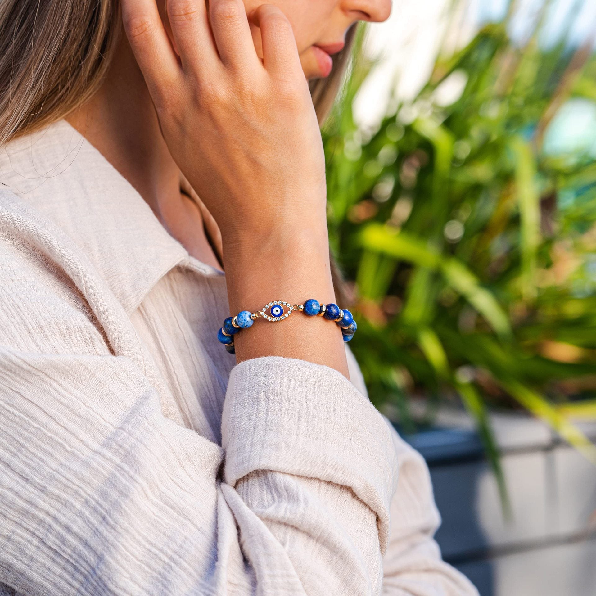 Bracelet en Lapis Lazuli avec un œil bleu et blanc au centre, porté au poignet d'une femme.