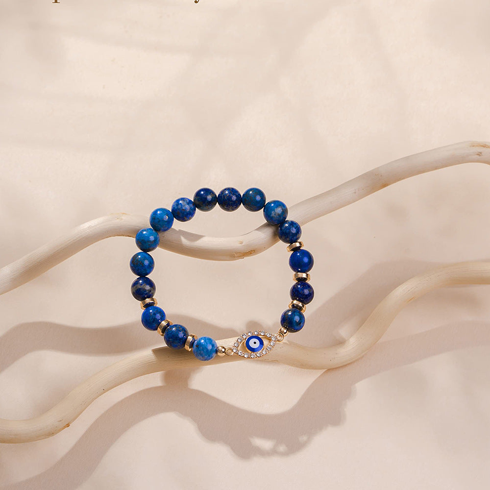 Bracelet perles bleues en lapis lazuli avec un fermoir œil bleu serti de strass et des intercalaires dorés.