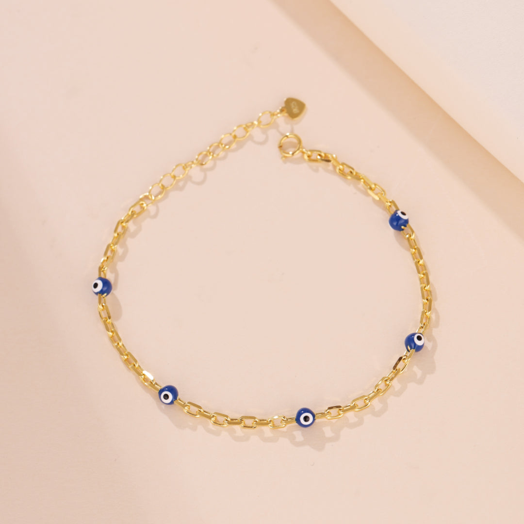 Bracelet en argent 925 plaqué or avec des breloques œil bleu, chaîne à maillons rectangulaires, fermoir mousqueton et réglage de longueur.