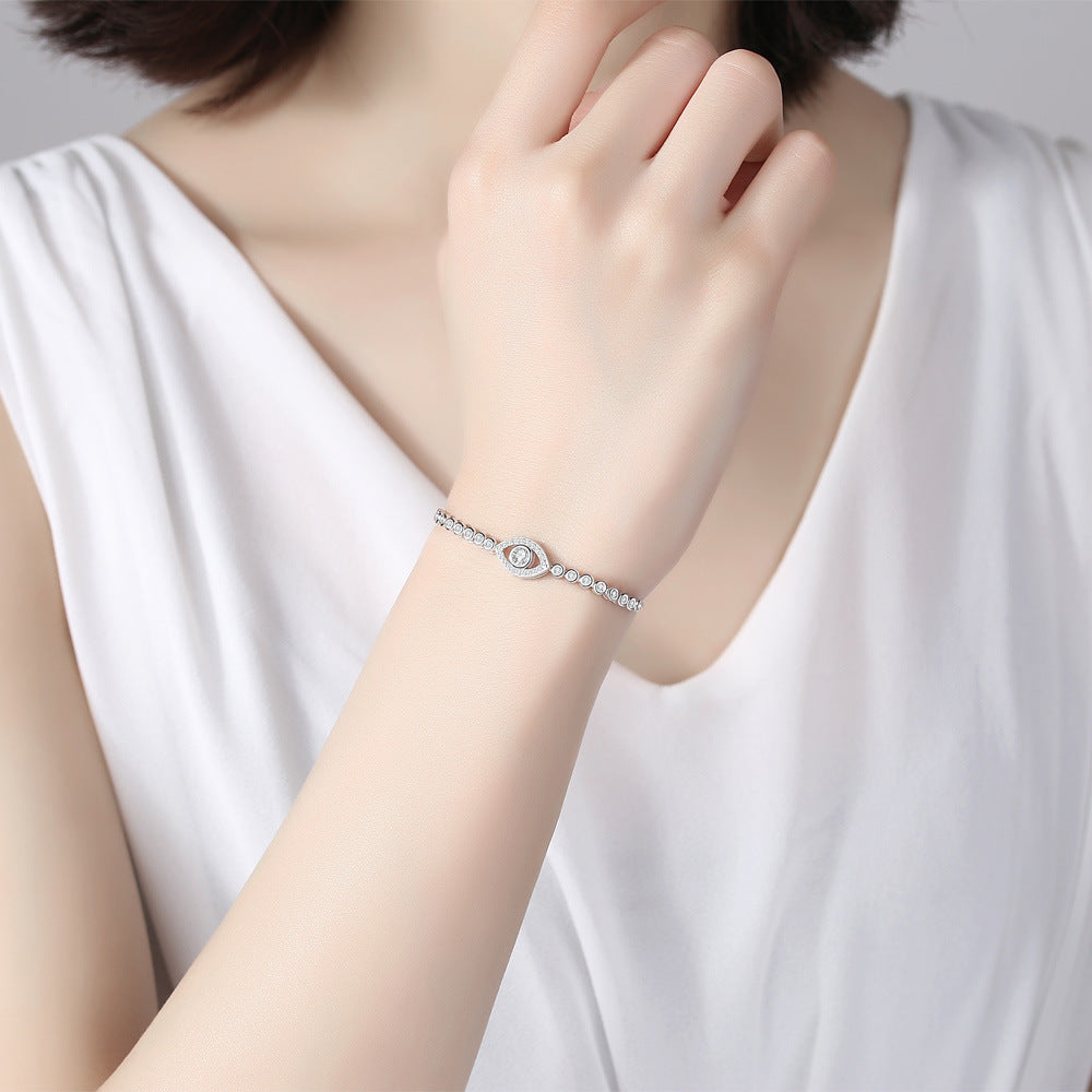 Bracelet œil mystérieux en argent orné de cristaux brillants, porté au poignet d'une femme