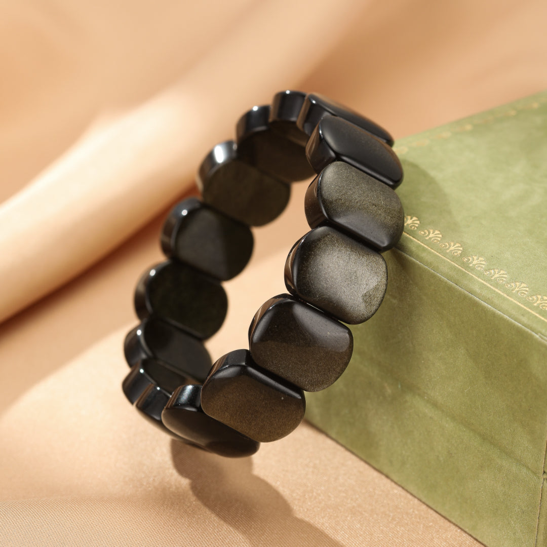Bracelet fait de pierres d'obsidienne dorée polies et facettées, montées sur un élastique.
