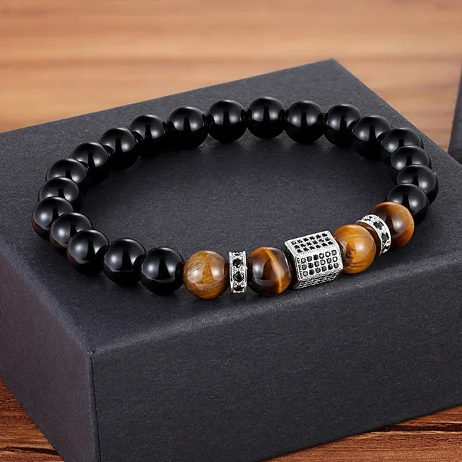 Bracelet avec des perles noires d'onyx et des perles œil de tigre, un élément central argenté de forme hexagonale et des accents de zircon.