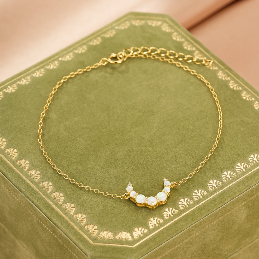 Bracelet fin en argent 925 plaqué or 18K orné d'une demi-lune sertie de multiples opales blanches et de cristaux scintillants.